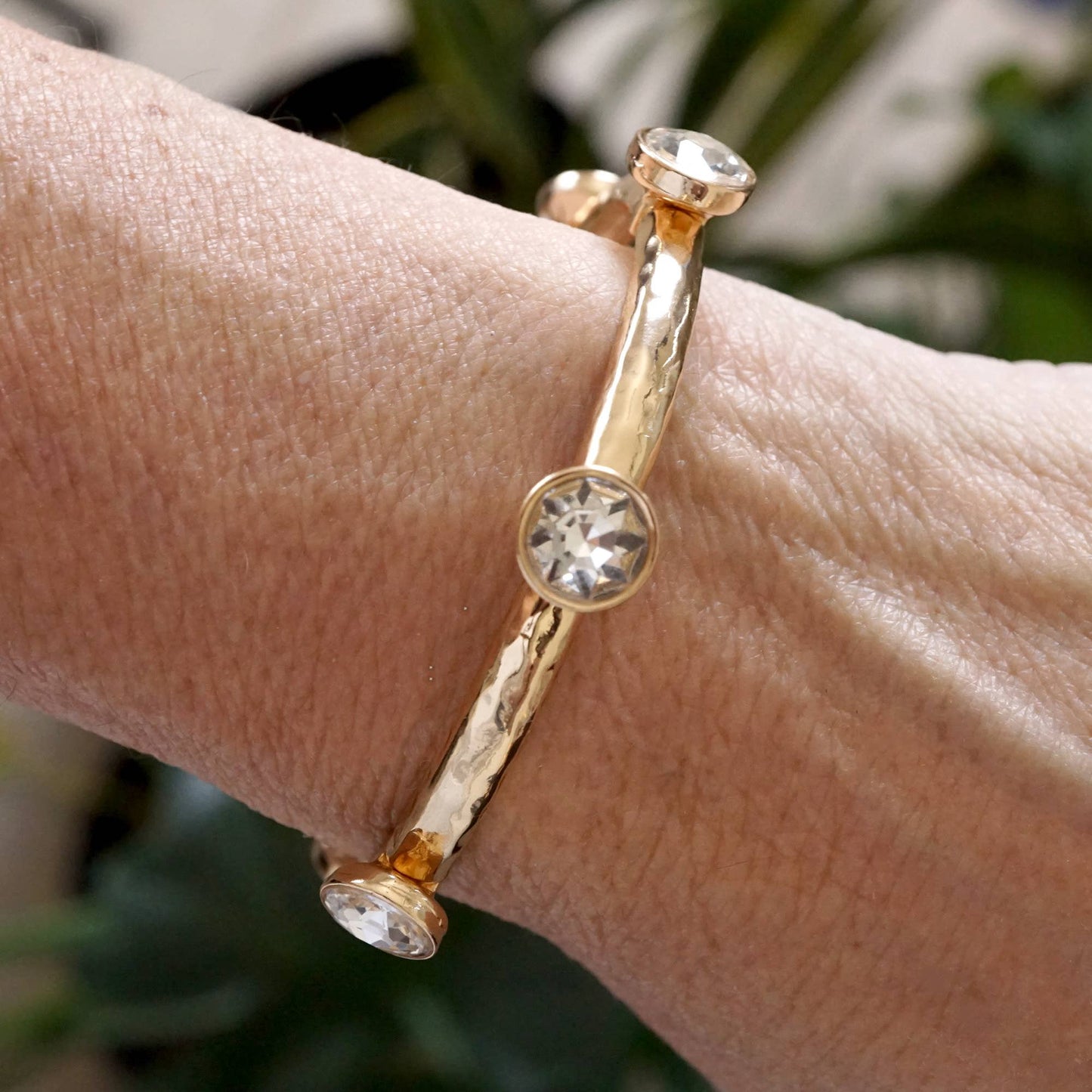Brazalete de cristales transparentes brillantes en tono dorado o plateado.