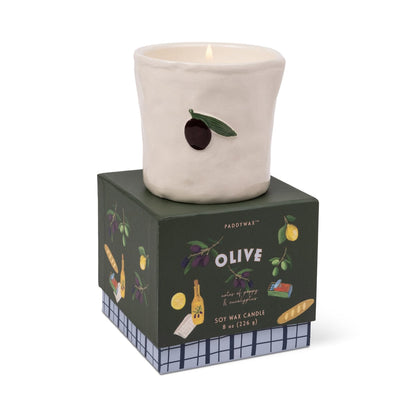 Fig & Olive Bistro Candle 8 oz, A lit ceramic candle with a hand-painted olive and leaf stands on its green Fig and Olive box.