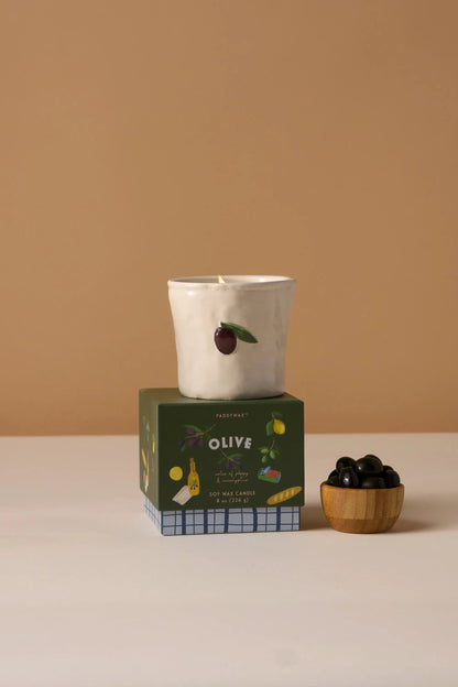 Fig & Olive Bistro Candle 8 oz, A lit ceramic candle with a hand-painted olive and leaf stands on its green Fig and Olive box.