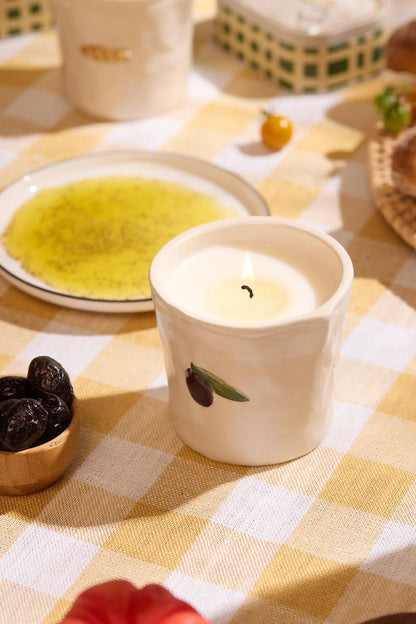 Fig & Olive Bistro Candle 8 oz, A lit ceramic candle with a hand-painted olive and leaf stands on its green Fig and Olive box.
