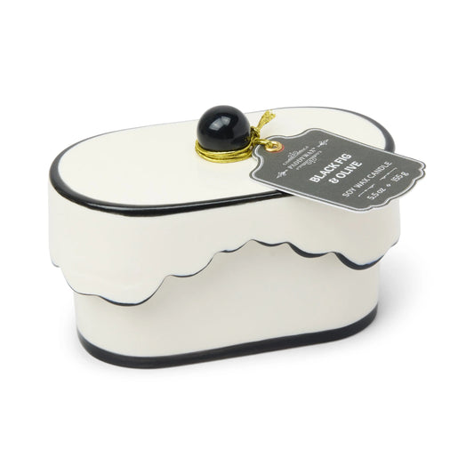 Chérie 5.5 oz Ceramic Candle, A white ceramic lidded candle box with a black scalloped rim and a round knob, tagged Black Fig and Olive.