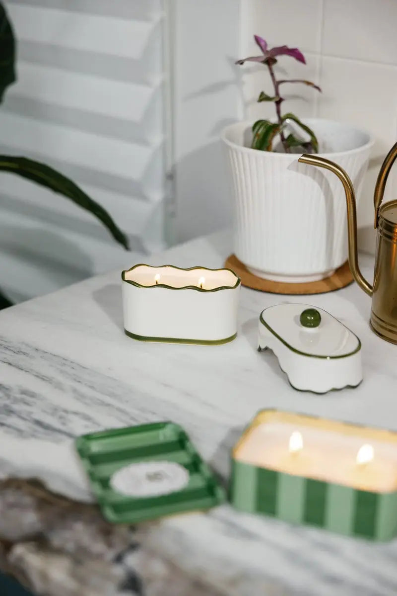 Chérie 5.5 oz Ceramic Candle, A white ceramic lidded candle box with a black scalloped rim and a round knob, tagged Black Fig and Olive.