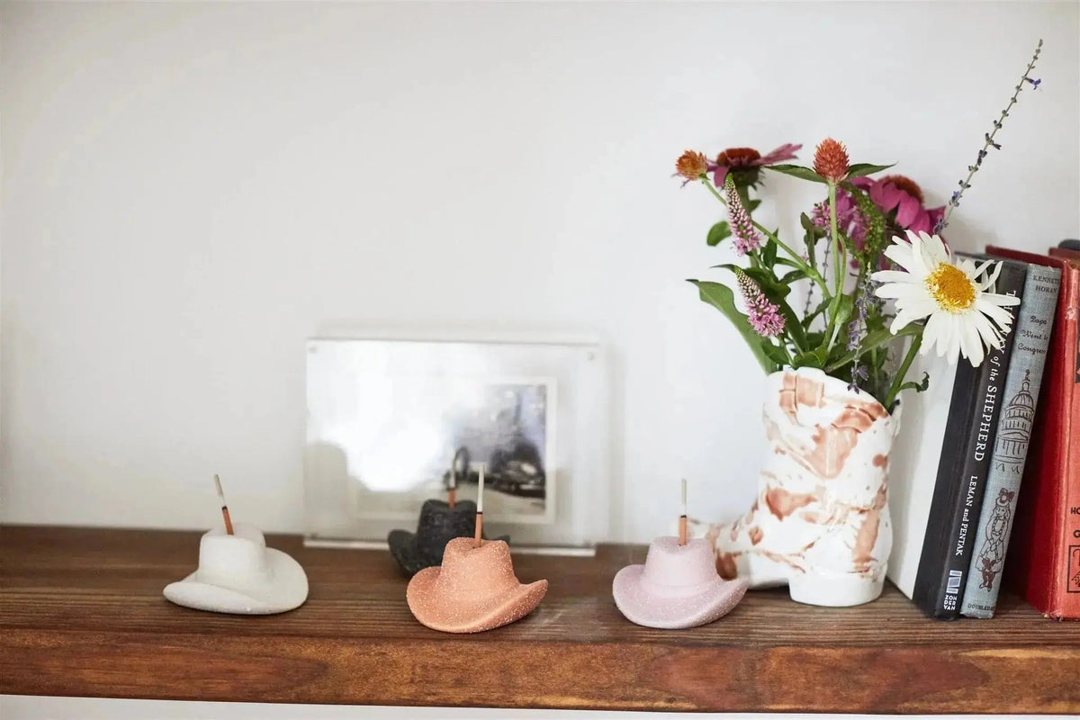 Teak & Tobacco Cowboy Hat Incense Holder, A terracotta ceramic cowboy hat incense holder with one incense stick standing in the crown, next to its kraft packaging box.