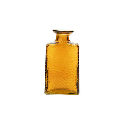Norma Amber Glass Bud Vase, An amber glass bud vase with a textured surface and a short flared neck, empty against a white background.