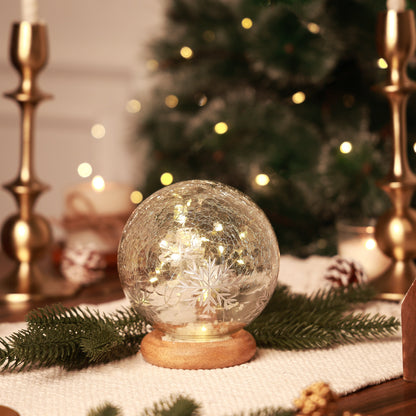 Adonis Snow Globe, A clear, crackled glass snow globe patterned with white snowflakes, set on a round natural wood base.