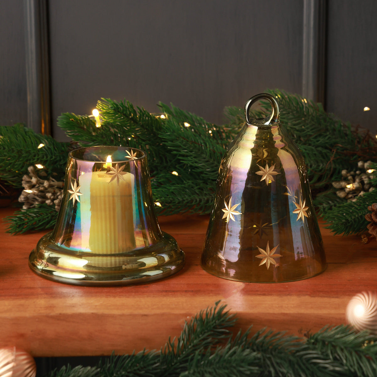 Tinsel Glass Bell Candle Holder, A green iridescent glass bell shaped candle holder with small gold stars and a ring on top, shown whole on its matching glass base.