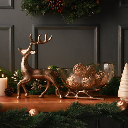 Nordelle Reindeer Sleigh, A champagne gold metal reindeer pulling a clear glass sleigh-shaped dish on champagne gold metal runners.