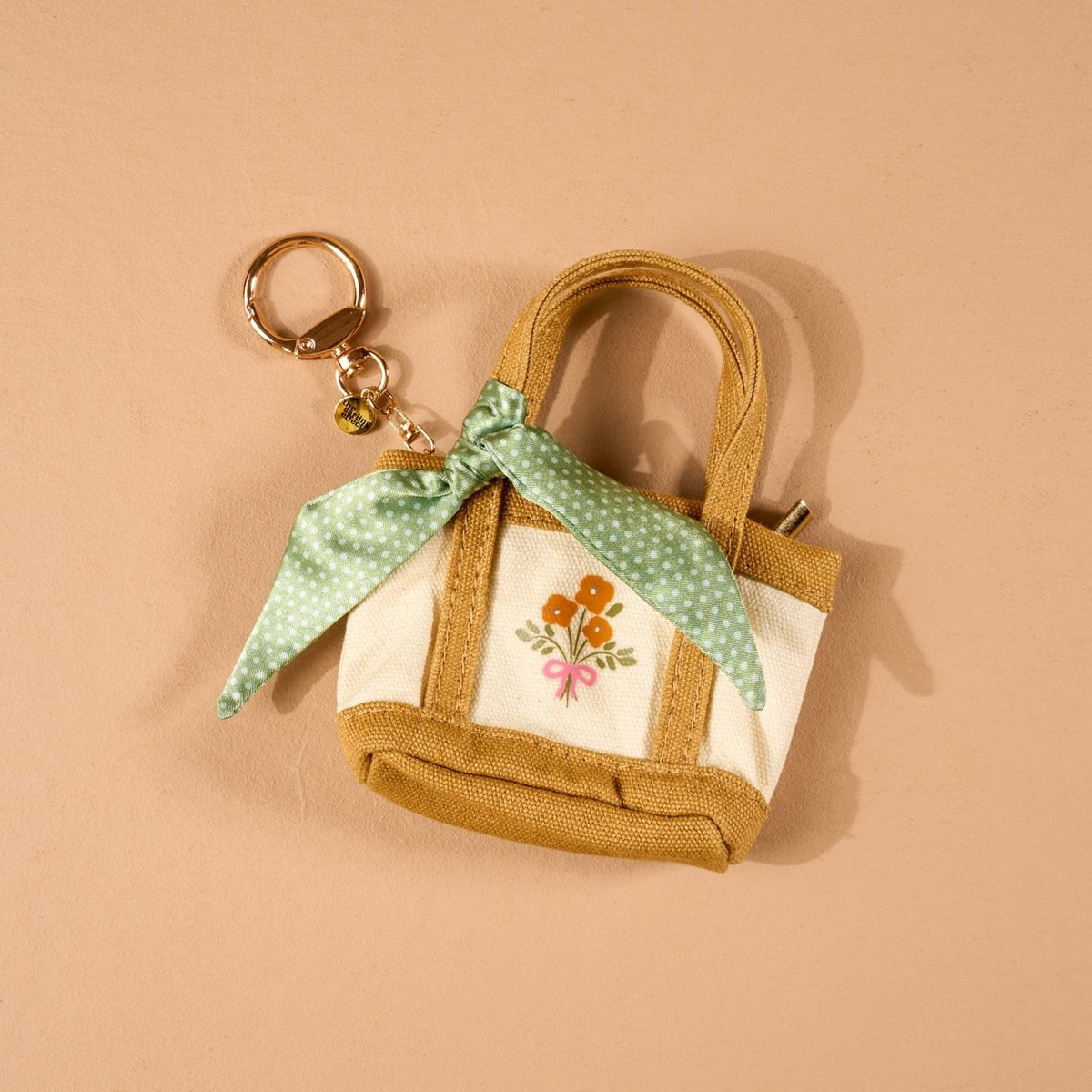 Tiny Tote Bag Charm, A miniature tan and cream canvas style tote bag charm with an orange floral bouquet print and gold tone hardware, in the Honey Blossom design.