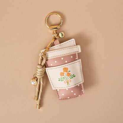 Vegan Leather Bag Charm, A dog shaped bag charm in cognac vegan leather with floppy ears, a small collar tag, and a burgundy cord tassel with a pearl bead.