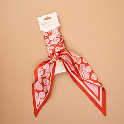 Twirl & Tie Scarf Accessory, A red and white gingham satin scarf tied in a knot, showing a red polka dot pattern on the reverse side of the tails.