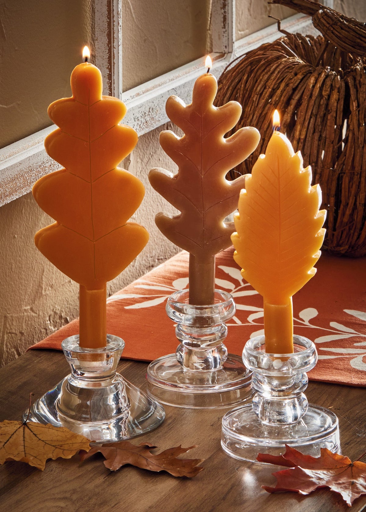 Fall Leaf Taper Set of Three, Photo shows three taper candles shaped like leaves in orange, brown, and gold, each with a raised vein pattern.