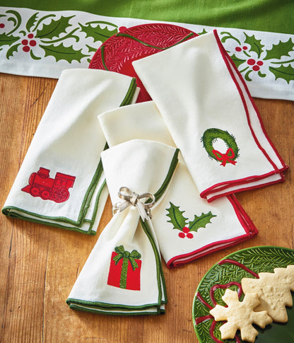 Christmastime Embroidered Napkin Set of Four, Photo shows four white napkins folded together, each embroidered with a different Christmas icon and trimmed in red or green satin.