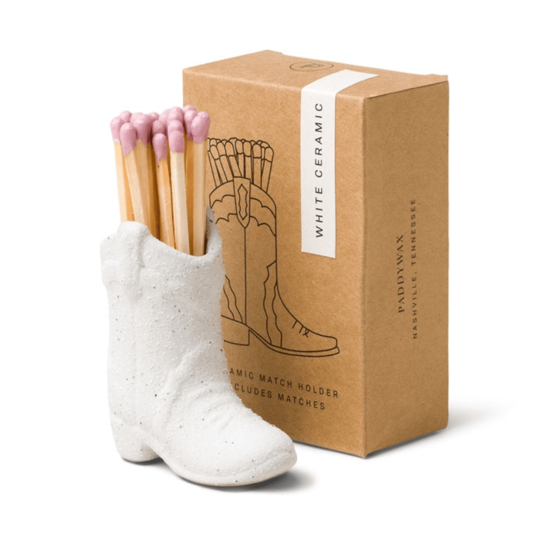 Cowboy Boot Match Holder, A matte white ceramic cowboy boot holds a bundle of pink-tipped matches beside its kraft packaging box.