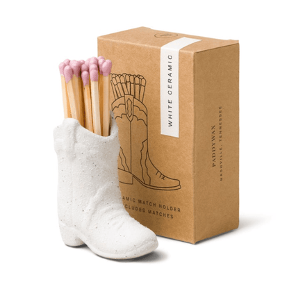 Cowboy Boot Match Holder, A matte white ceramic cowboy boot holds a bundle of pink-tipped matches beside its kraft packaging box.