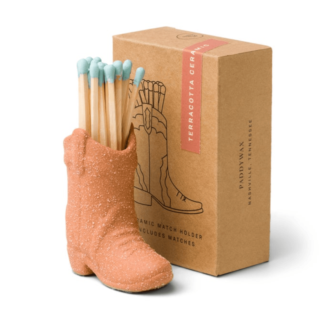 Cowboy Boot Match Holder, A matte white ceramic cowboy boot holds a bundle of pink-tipped matches beside its kraft packaging box.