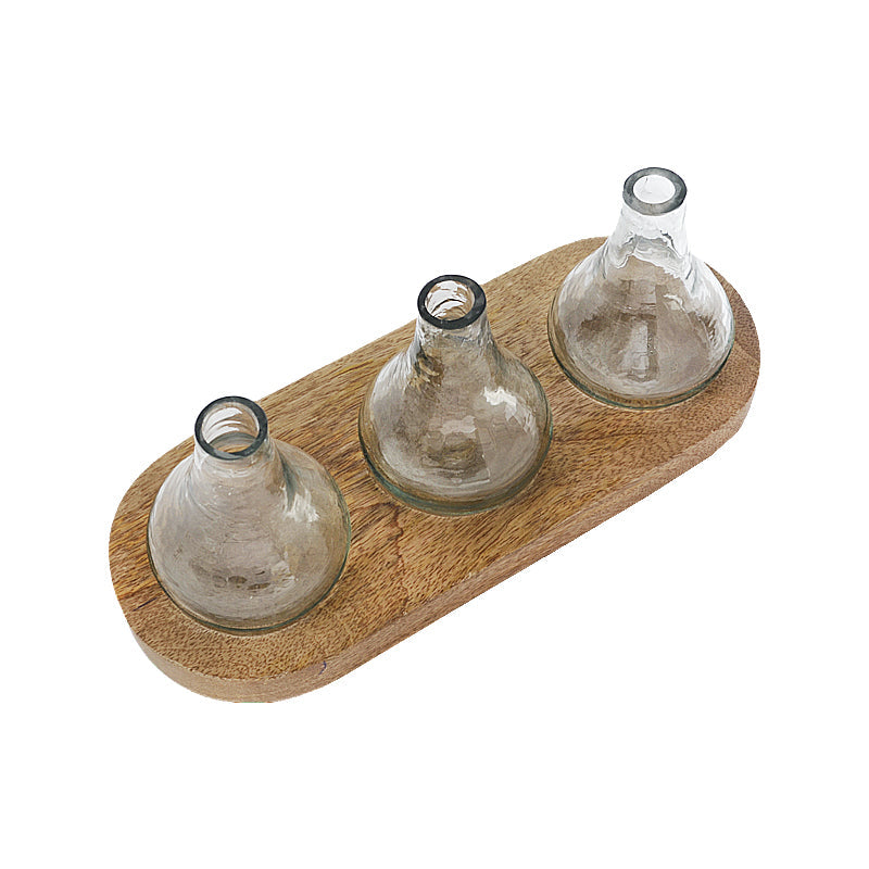 Dahlia Glass Bud Vase with Wooden Tray, Three clear glass bud vases, each a different shape, set on an oval mango wood tray against a white background.