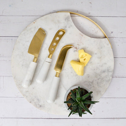 Calandiva Cheese Knife Set with White Stone Handles, Three cheese knives with gold-finish blades and white stone handles, laid side by side on a white background.