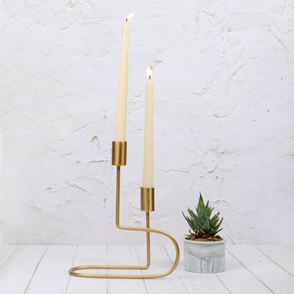Lily Double Taper Candle Holder, A gold metal double candle holder with a looping wire base and two candle cups at different heights, shown empty against a white background.