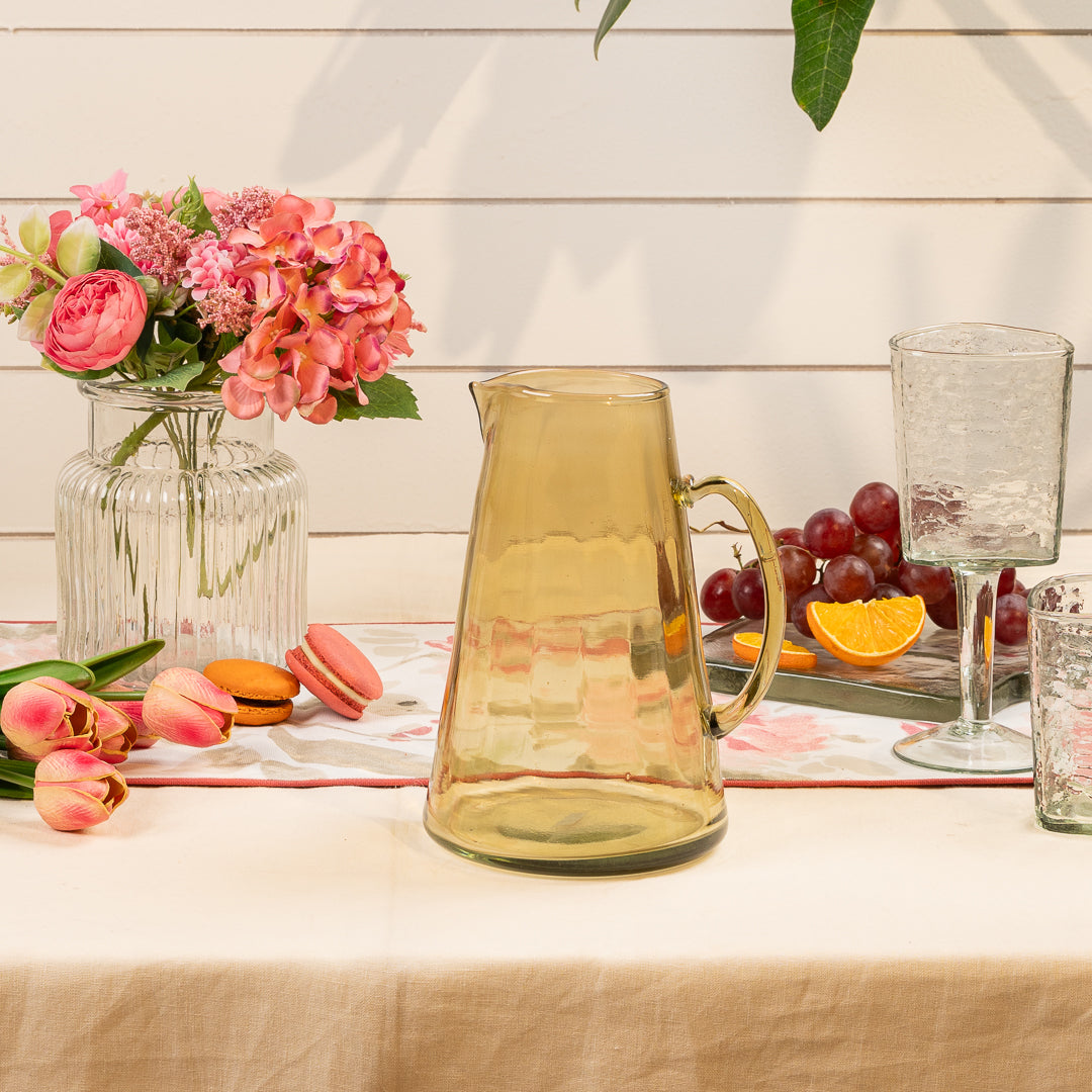 Sansa Olive Glass Jug, An olive recycled glass pitcher with a tapered body, a pinched spout, and a looped handle, on a white background.