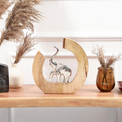 Ivy Elephant Figurine, A polished silver elephant figure with its trunk raised, set inside a crescent-shaped natural wood frame.