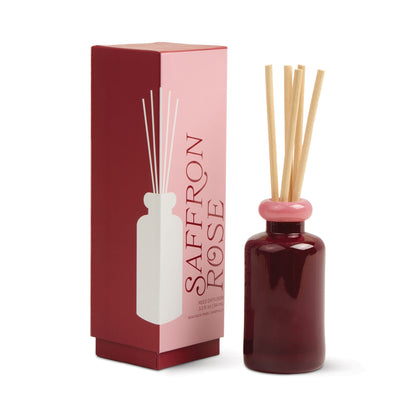 Stack 3.2 oz Diffuser, A maroon glass reed diffuser bottle with pink topped reeds standing next to its packaging box labeled Saffron Rose.