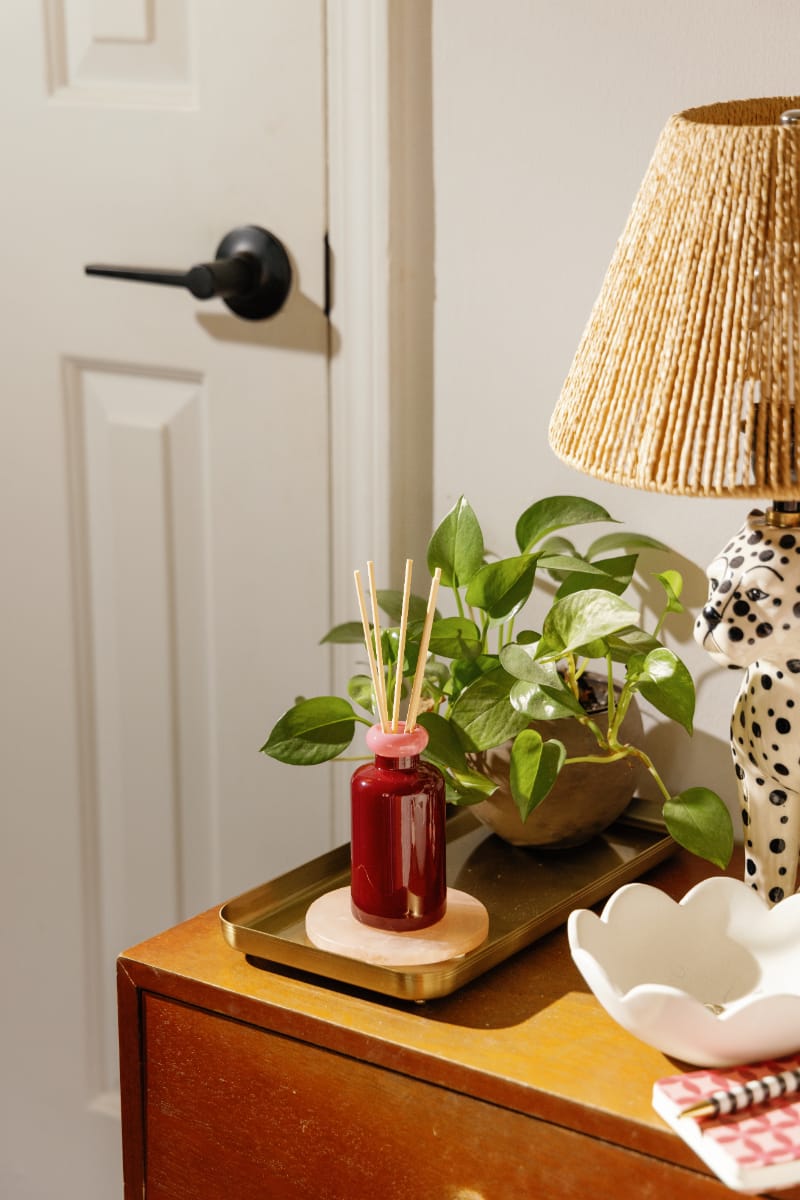 Stack 3.2 oz Diffuser, A maroon glass reed diffuser bottle with pink topped reeds standing next to its packaging box labeled Saffron Rose.