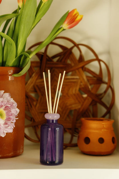 Stack 3.2 oz Diffuser, A maroon glass reed diffuser bottle with pink topped reeds standing next to its packaging box labeled Saffron Rose.