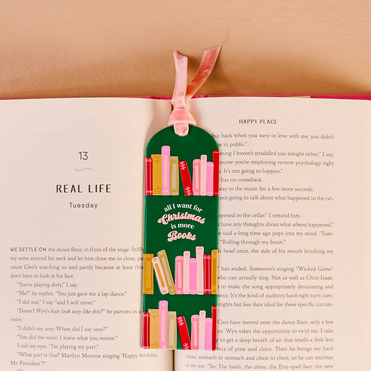 All I Want for Christmas Is More Books Acrylic Bookmark, An acrylic bookmark on its packaging card, printed with book spines and the words all I want for Christmas is more books, tied with a pink velvet ribbon.