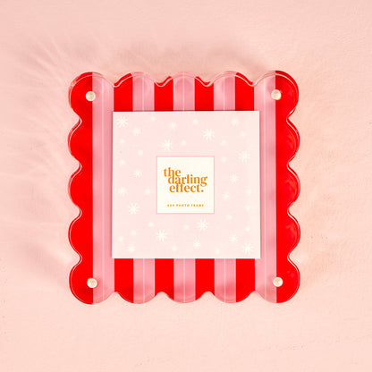 A square acrylic picture frame with a red and pink striped scalloped edge and pearl-style corner dots, holding a 4x4 photo card.