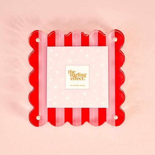 A square acrylic picture frame with a red and pink striped scalloped edge and pearl-style corner dots, holding a 4x4 photo card.