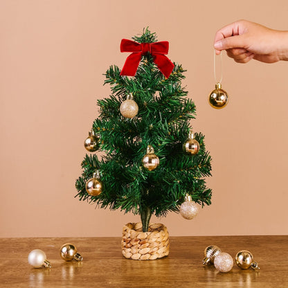 Green Mini Artificial Christmas Tree, A small artificial Christmas tree with full green branches, a red velvet bow at the top, and a woven basket base.