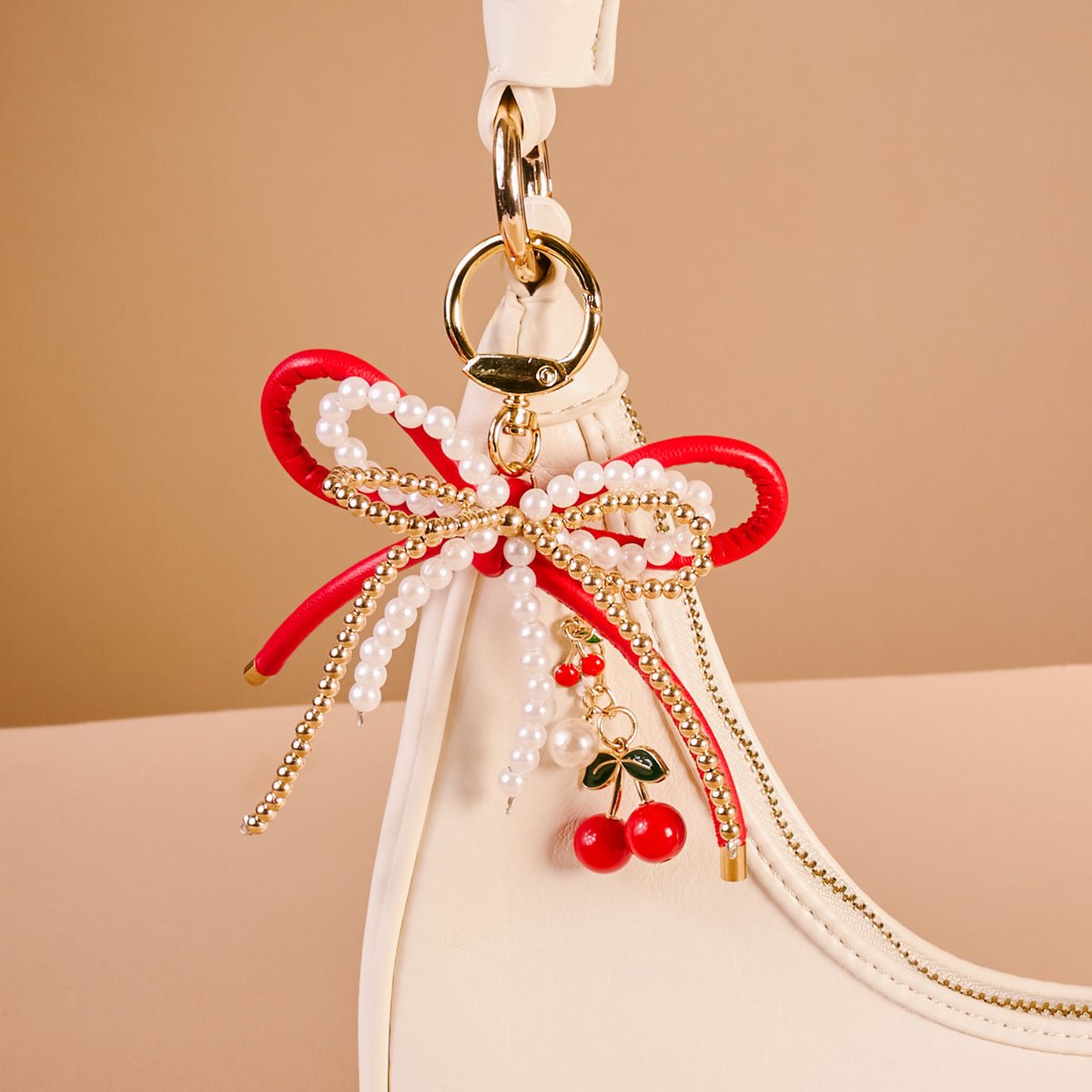 Layered Bows Bag Charm, A black bow bag charm strung with pearl and gold beads and finished with a small black flower and heart charm, clipped to a gold keyring.