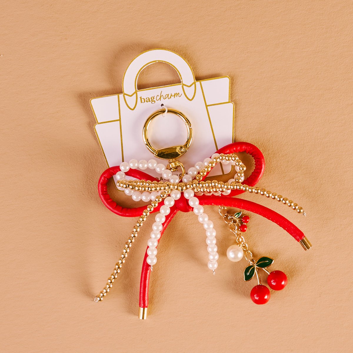 Layered Bows Bag Charm, A black bow bag charm strung with pearl and gold beads and finished with a small black flower and heart charm, clipped to a gold keyring.