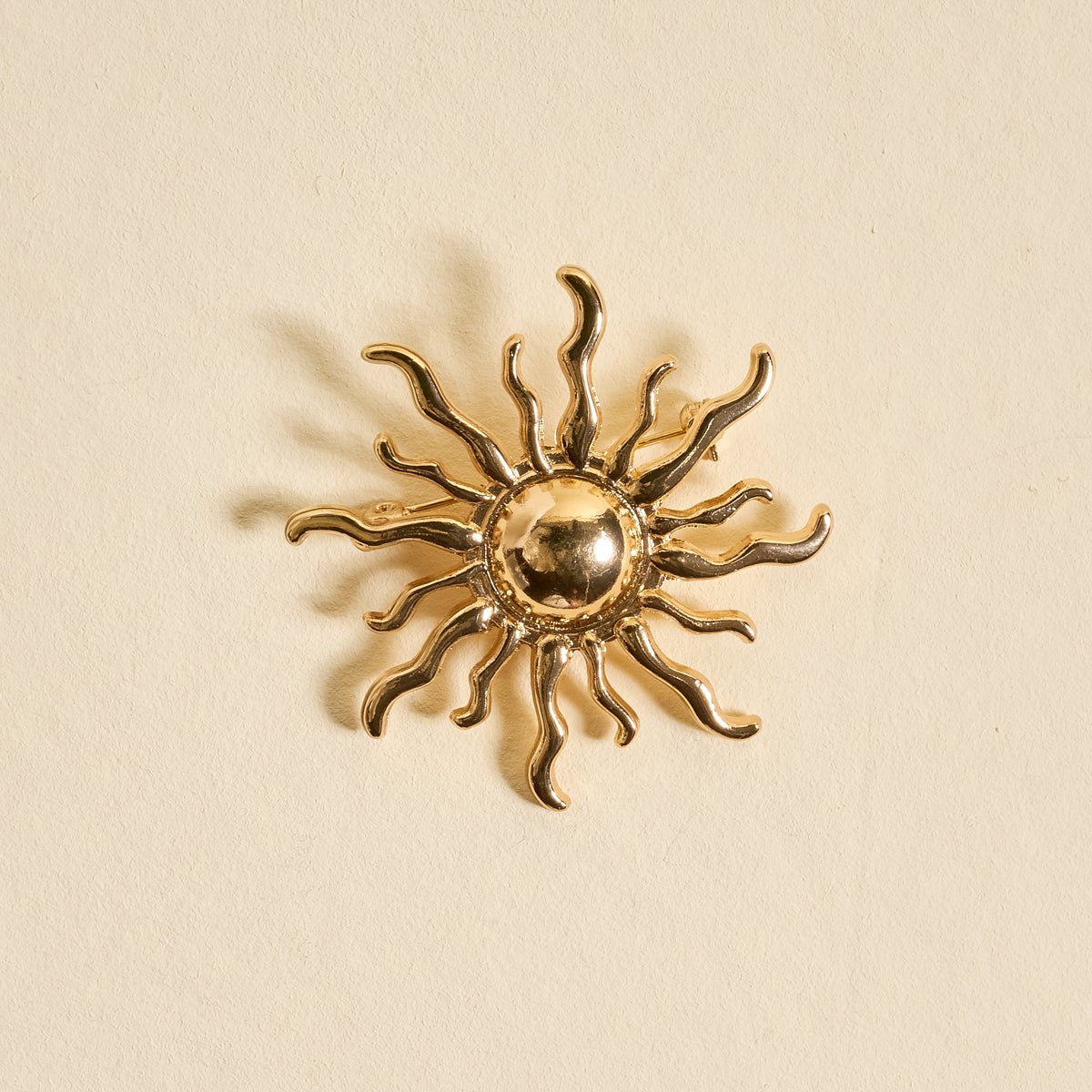 Timeless Brooch, A small gold brooch pin shaped like a teddy bear and covered edge to edge in clear rhinestones, with a gold bow at its neck, shown on a tan background.