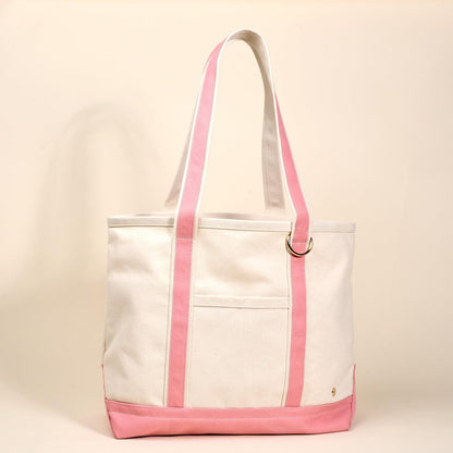 The Signature Canvas Tote Bag, A natural canvas tote bag with black webbing straps, a front pocket, and a gold D-ring, shown against a cream background.