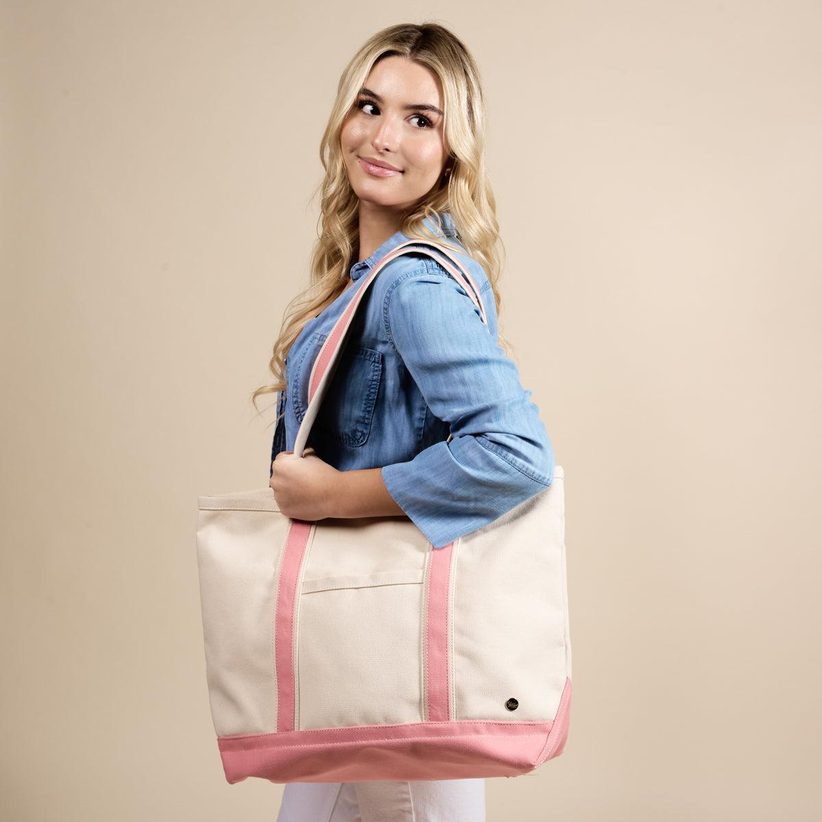 The Signature Canvas Tote Bag, A natural canvas tote bag with black webbing straps, a front pocket, and a gold D-ring, shown against a cream background.