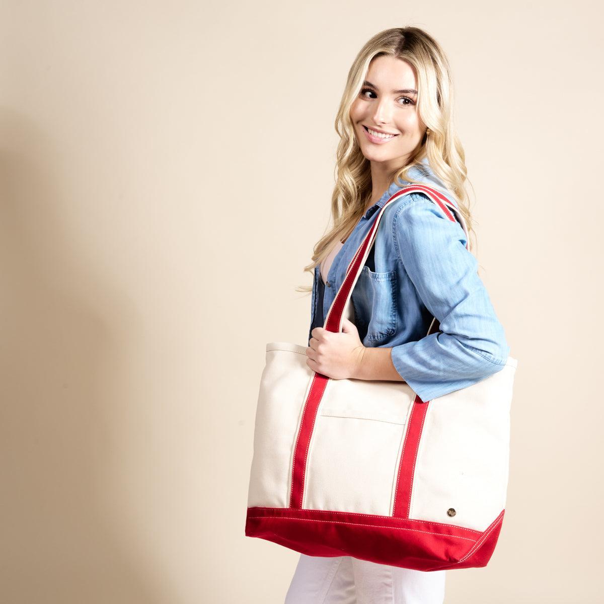 The Signature Canvas Tote Bag, A natural canvas tote bag with black webbing straps, a front pocket, and a gold D-ring, shown against a cream background.