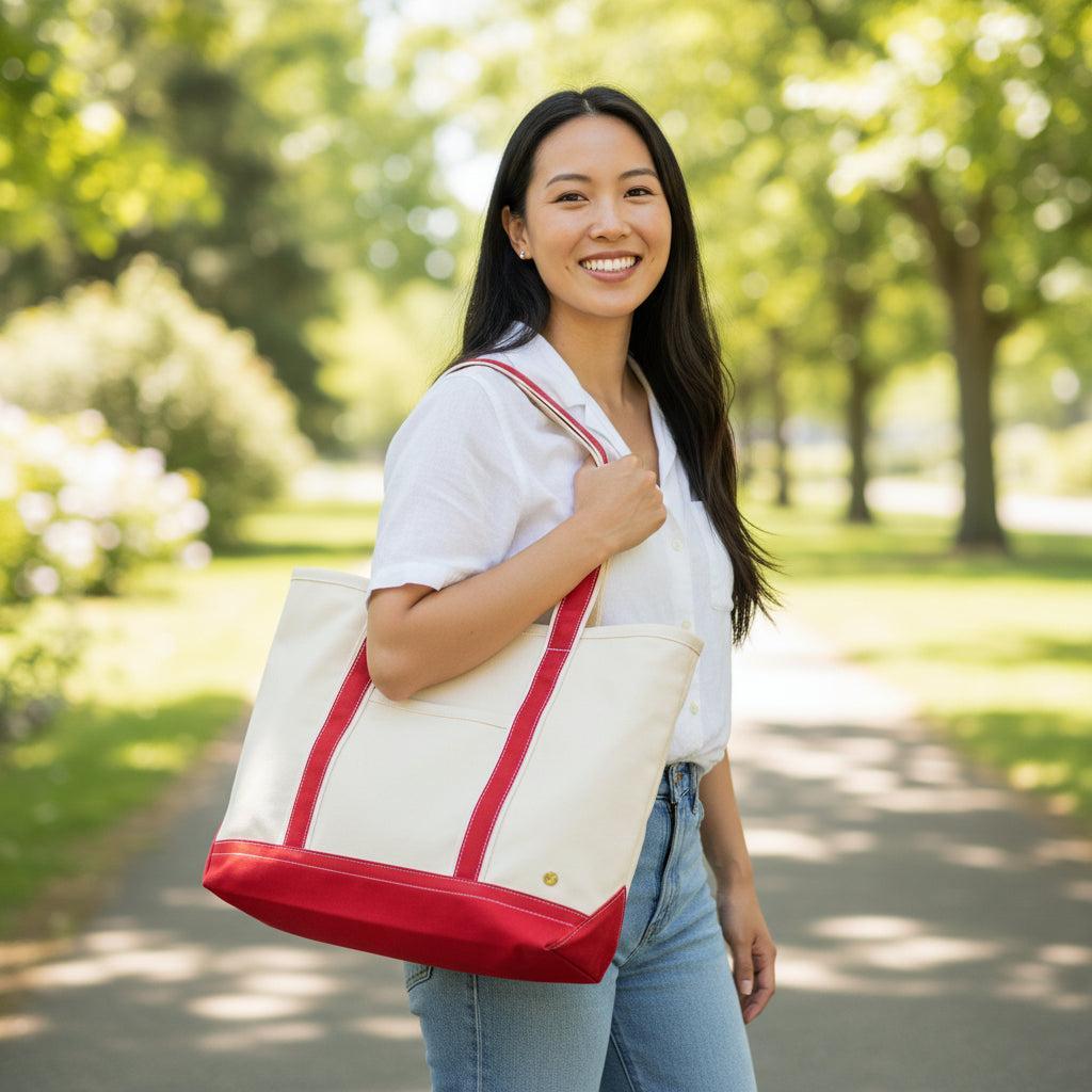 The Signature Canvas Tote Bag, A natural canvas tote bag with black webbing straps, a front pocket, and a gold D-ring, shown against a cream background.