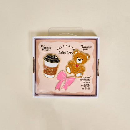 Enamel Pin Pack, A boxed set of three gold enamel pins in the Latte Love design, a coffee cup, a teddy bear, and a pink bow.