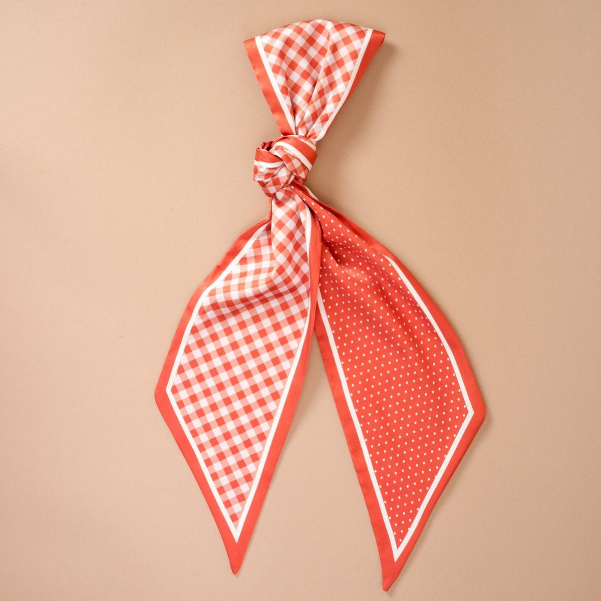 Twirl & Tie Scarf Accessory, A red and white gingham satin scarf tied in a knot, showing a red polka dot pattern on the reverse side of the tails.