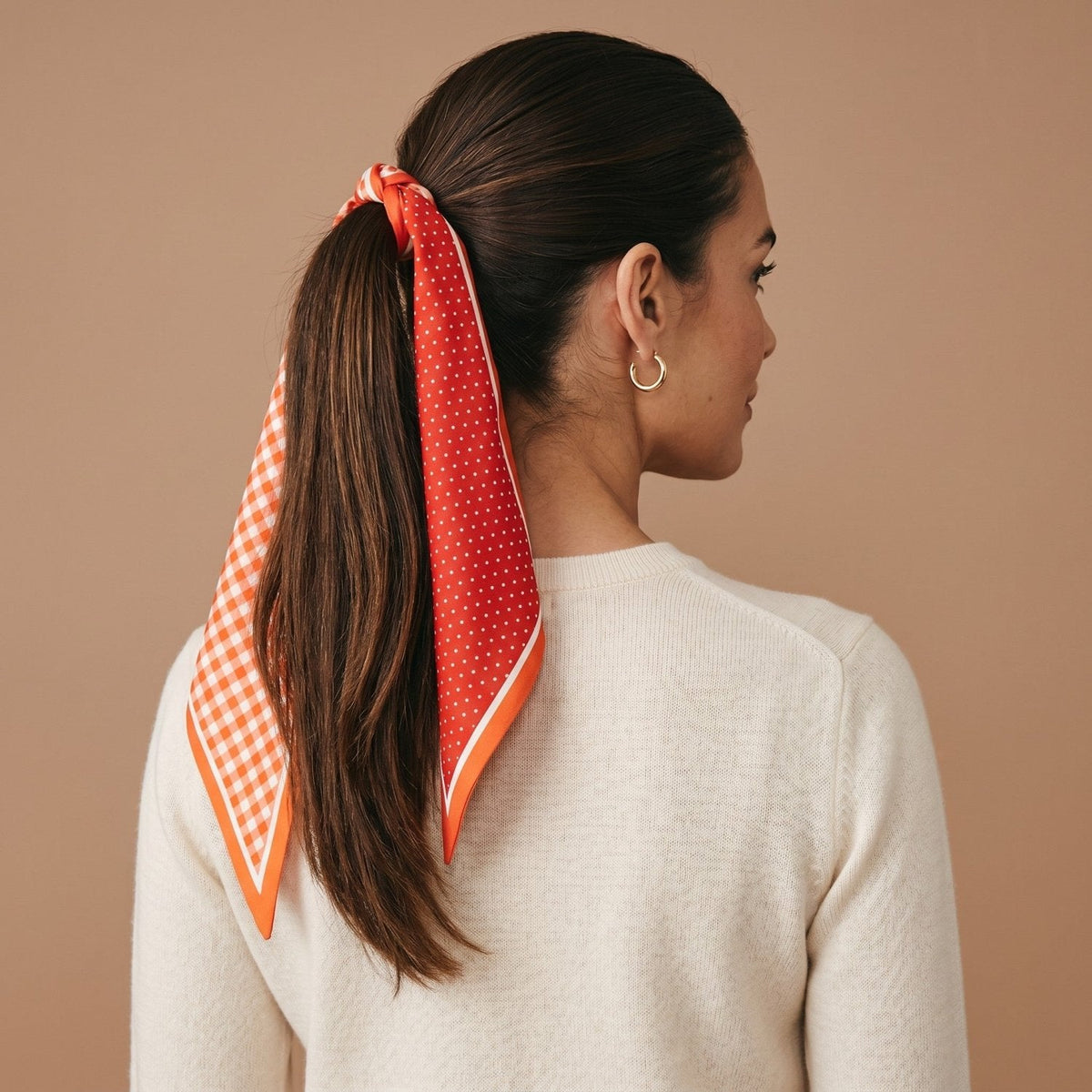 Twirl & Tie Scarf Accessory, A red and white gingham satin scarf tied in a knot, showing a red polka dot pattern on the reverse side of the tails.