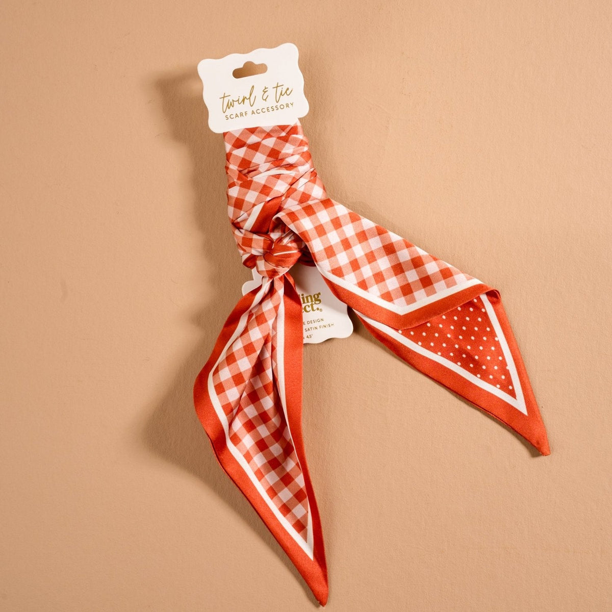 Twirl & Tie Scarf Accessory, A red and white gingham satin scarf tied in a knot, showing a red polka dot pattern on the reverse side of the tails.