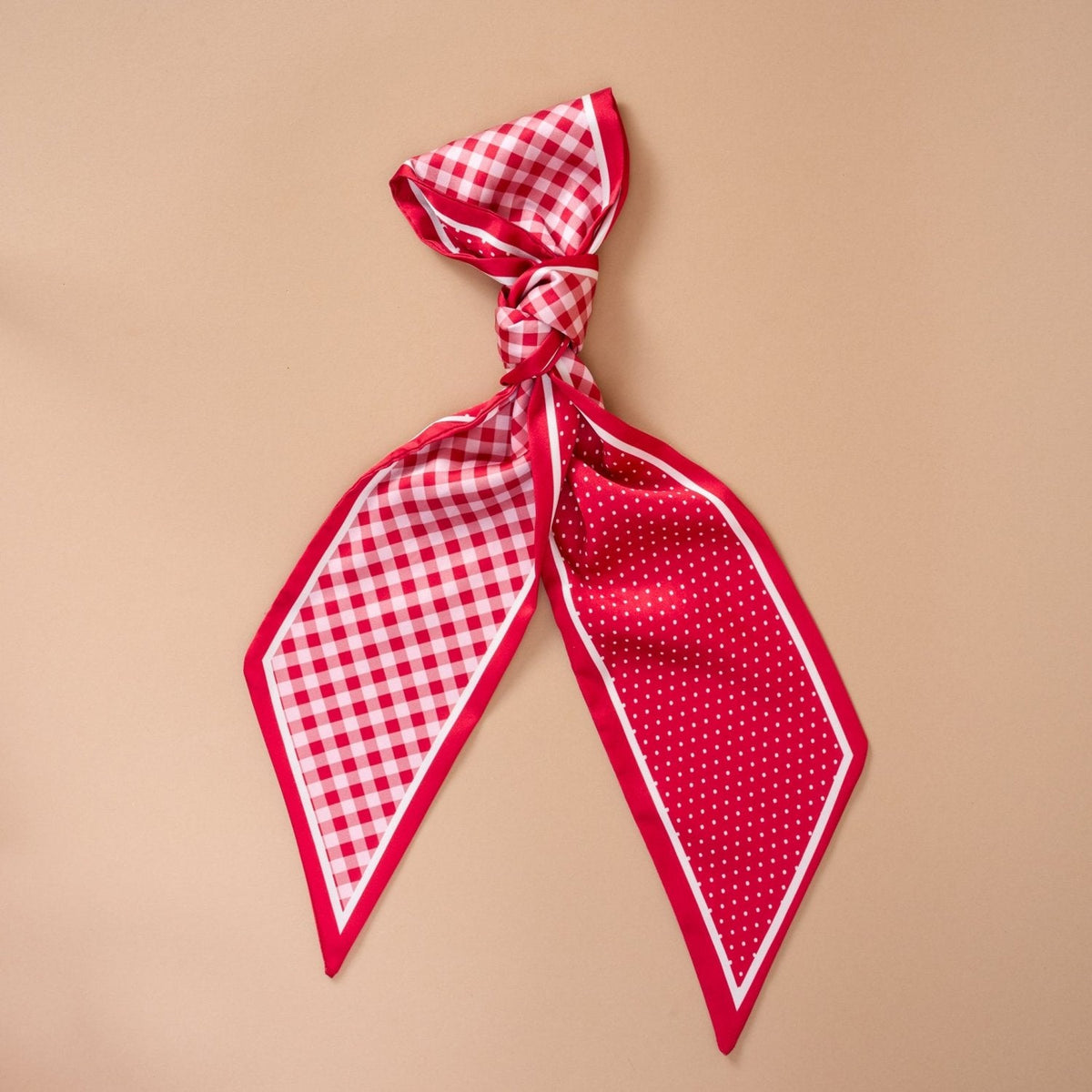 Twirl & Tie Scarf Accessory, A red and white gingham satin scarf tied in a knot, showing a red polka dot pattern on the reverse side of the tails.