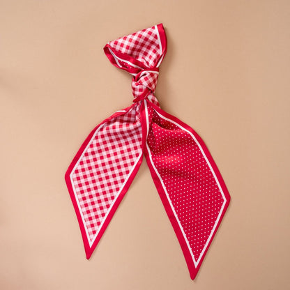 Twirl & Tie Scarf Accessory, A red and white gingham satin scarf tied in a knot, showing a red polka dot pattern on the reverse side of the tails.