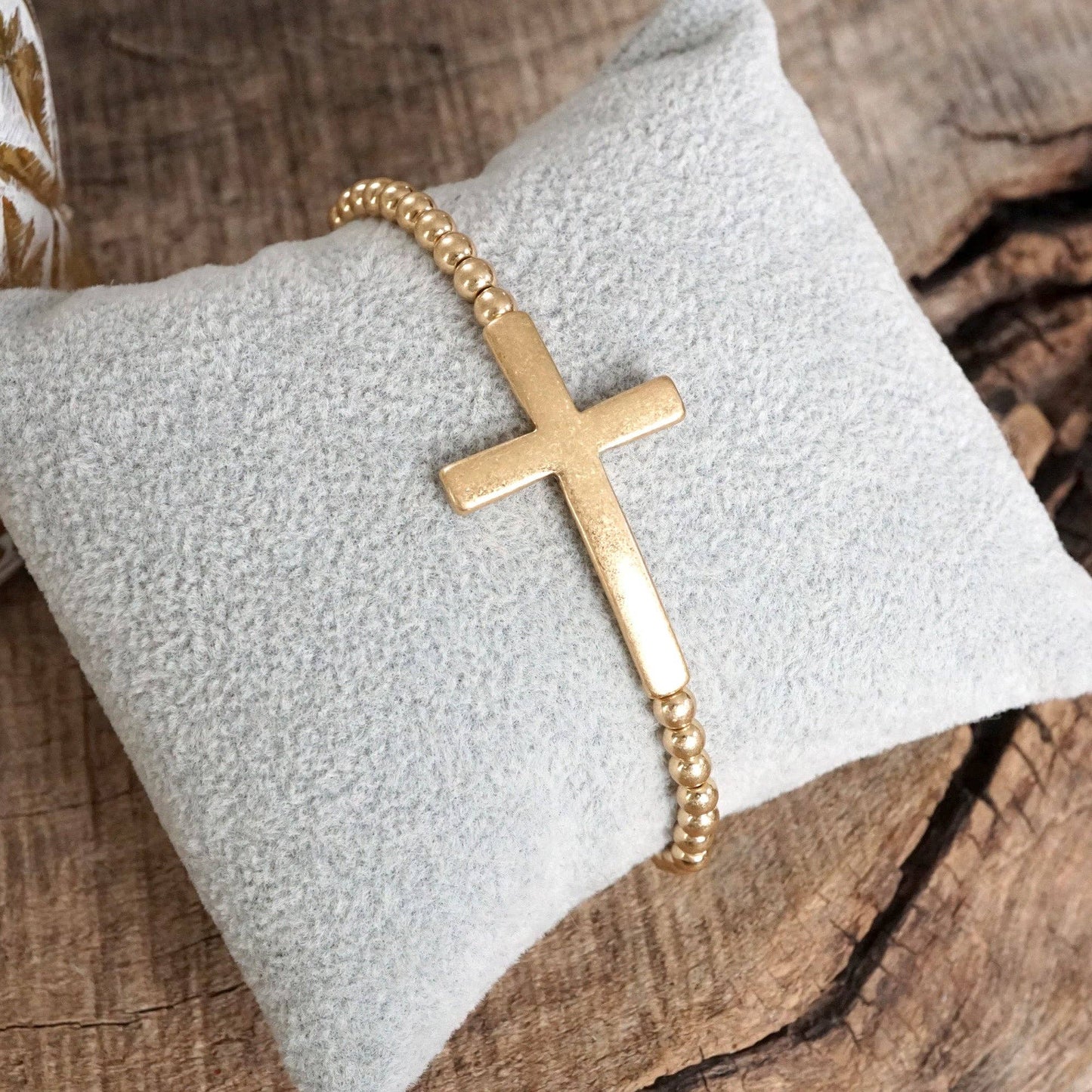 Pulsera elástica minimalista con cruz en tono dorado desgastado y cuentas de bola