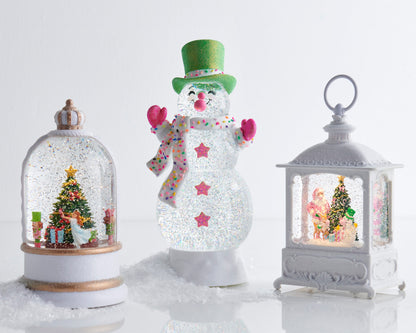Animated Musical Nutcracker Suite Lighted Water Globe, A white and gold crowned water globe showing a rotating figure in a white dress beside a decorated Christmas tree flanked by two nutcracker soldiers.
