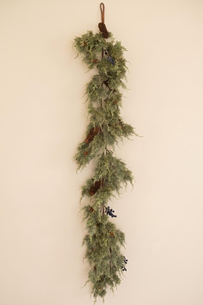 Artificial Juniper Christmas Garland with Berries, A faux juniper garland with red berries and pinecones laid out in a line.