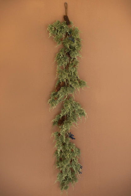 Artificial Juniper Christmas Garland with Berries, A faux juniper garland with red berries and pinecones laid out in a line.