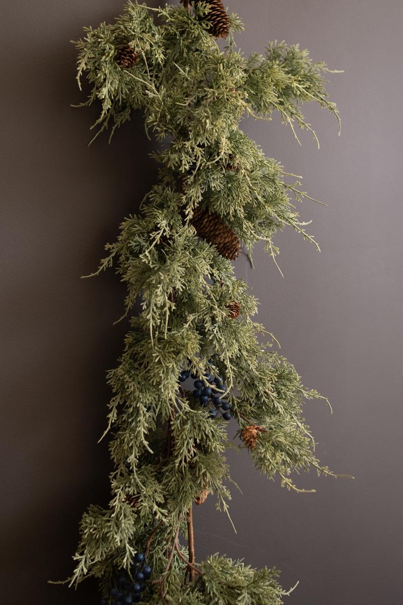 Artificial Juniper Christmas Garland with Berries, A faux juniper garland with red berries and pinecones laid out in a line.