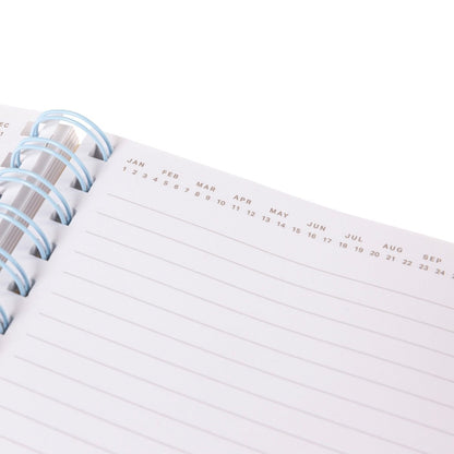 At Capacity Everyday Journal, A cream spiral-bound journal covered in rainbow smiley faces with the words i'm at capacity in colorful lettering at the center.